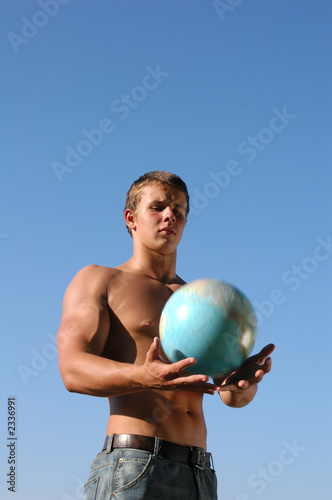 Fotografie young muscular man playing with a terrestrial globe