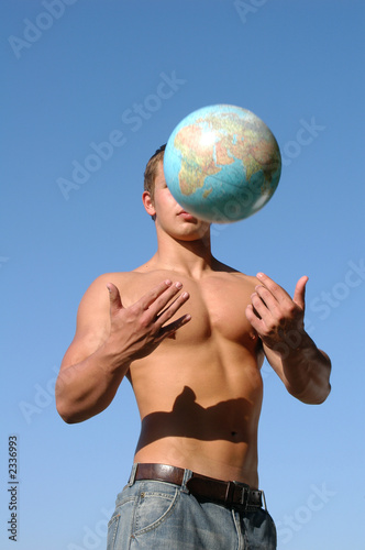 Obraz na plátně young muscular man playing with a terrestrial globe