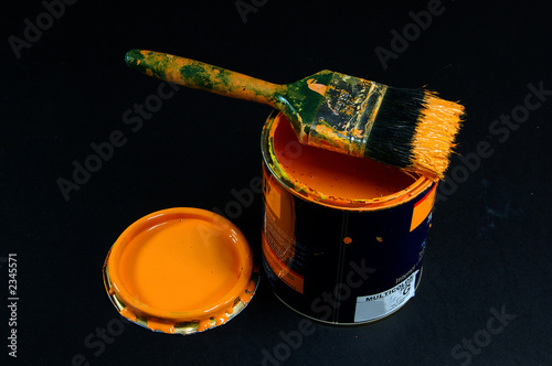can of yellow paint with brush