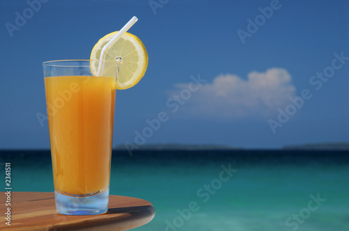 glass of mango juice with straw and lemon twist.