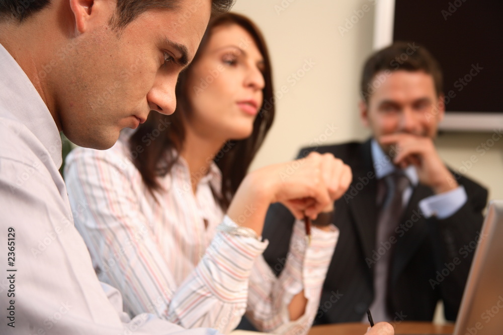 three peofessionals at a meeting - one man in focu three peofessionals at a meeting - one man in focu