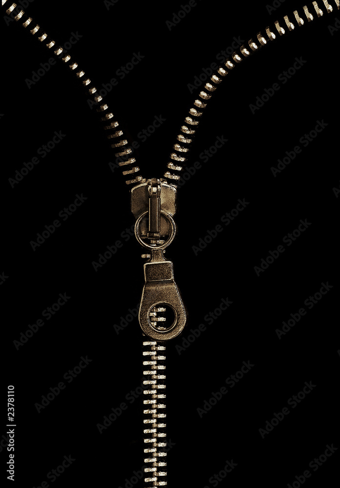 A metallic zipper can be seen against a clearly visible black background, and the pull tab is located in the center of the image.The lighting highlights the metallic shine of the zipper. A metallic zipper can be seen against a clearly visible black background, and the pull tab is located in the center of the image.The lighting highlights the metallic shine of the zipper.