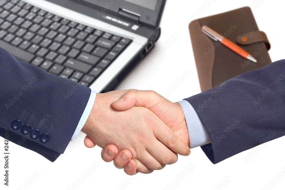 business handshake with a laptop and a notepad business handshake with a laptop and a notepad