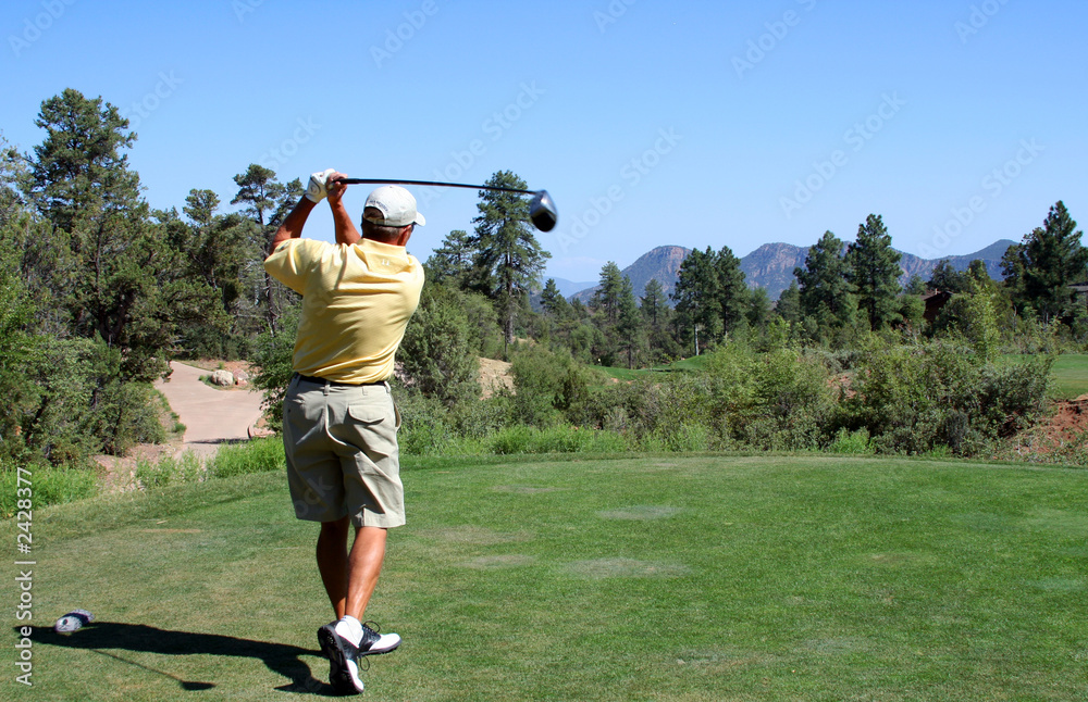 golfer teeing off in the mountains over a hazard golfer teeing off in the mountains over a hazard
