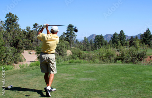 golfer teeing off in the mountains over a hazard