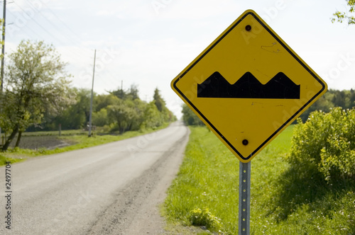 yellow caution sign warning bumpy road ahead