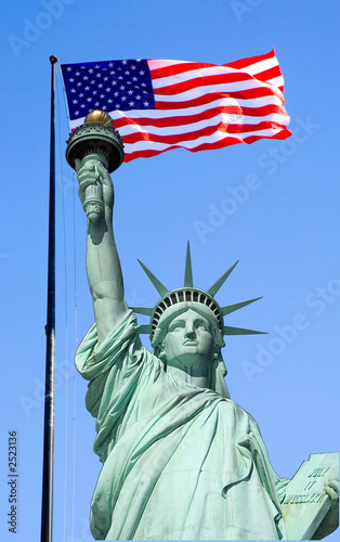 statue of liberty against blue sky with flag