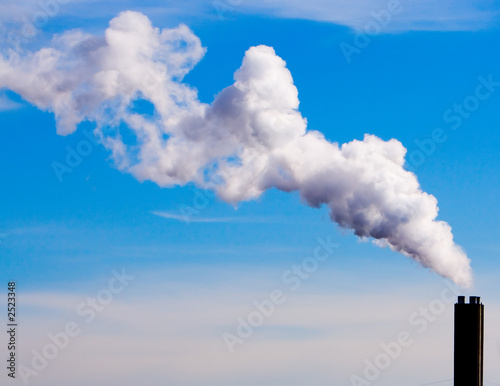 chimney billowing white smoke into blue sky