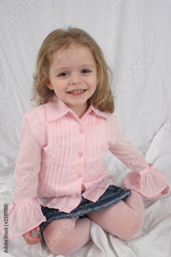 cute little girl sitting on white background.