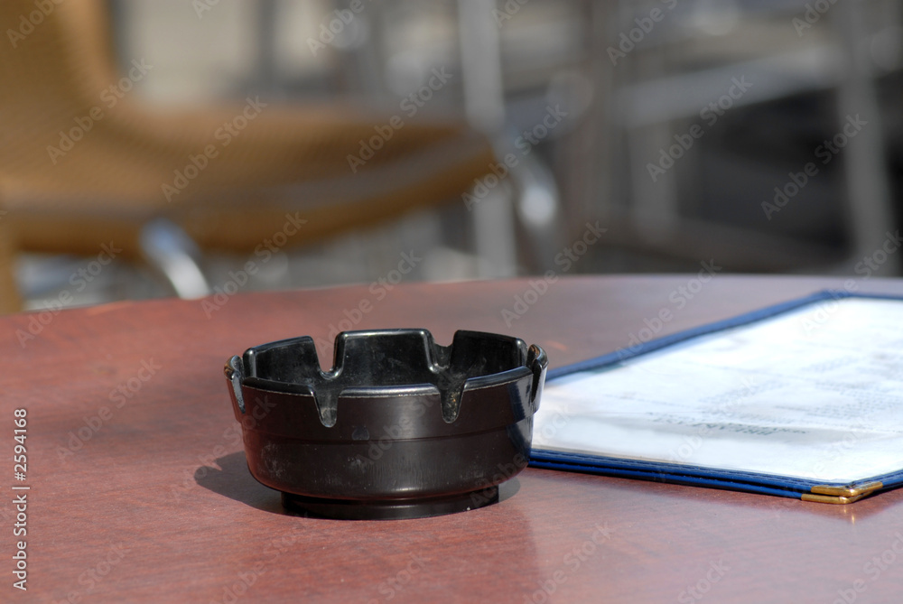 an ashtray and menu in a sidewalk cafe dining area an ashtray and menu in a sidewalk cafe dining area