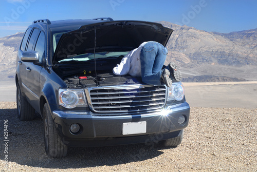 a woman looking into the engine area of her broken down vehicle