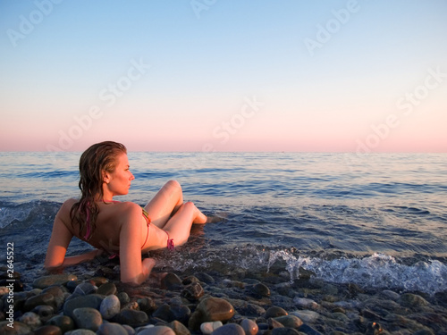 the woman lays in coastal waves