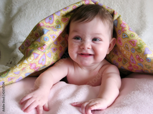 happy baby peeking out from under blanket