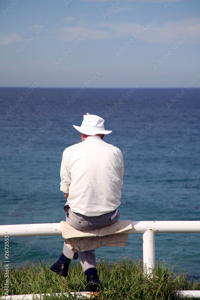 man sitting looking at ocean