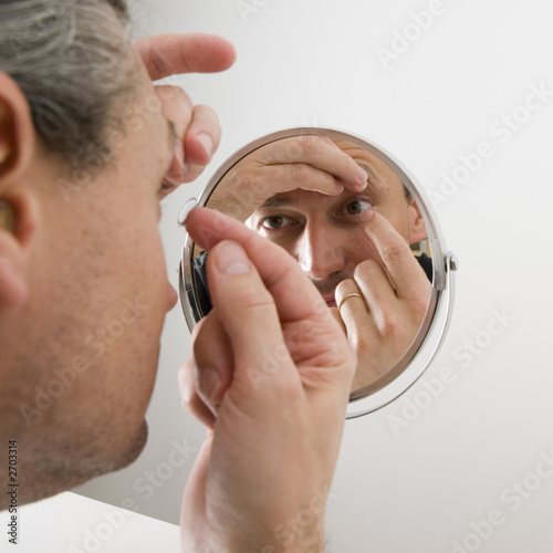 man inserting a contact lens in his eye