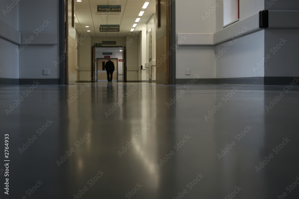 man walking along hospital corridor man walking along hospital corridor