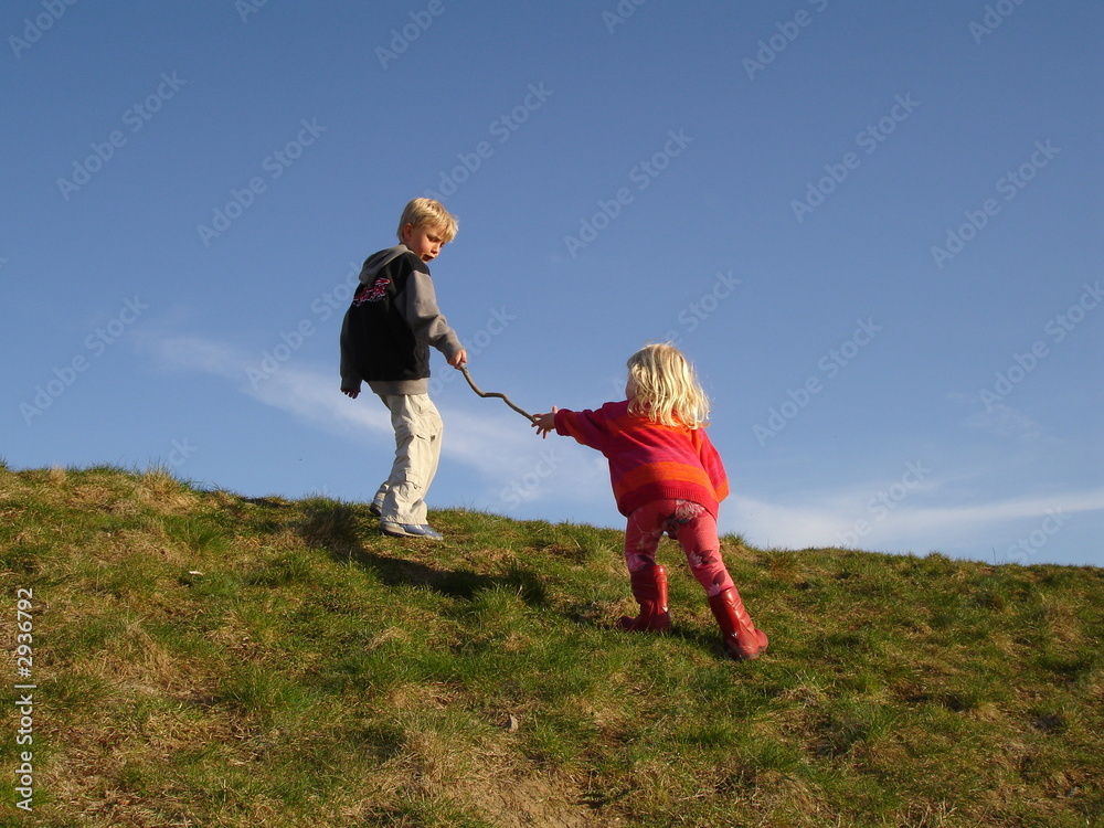 Little girl reaching out for help from her older, helpful brother