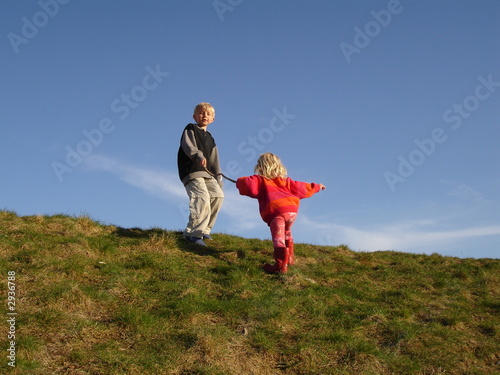 Big brother helping his little sister to get to the top of a hill