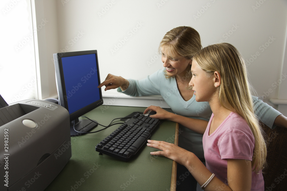 Naklejka premium Teenage girl and mom working on computer together.