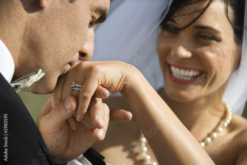 Groom kissing hand of smiling bride. photo