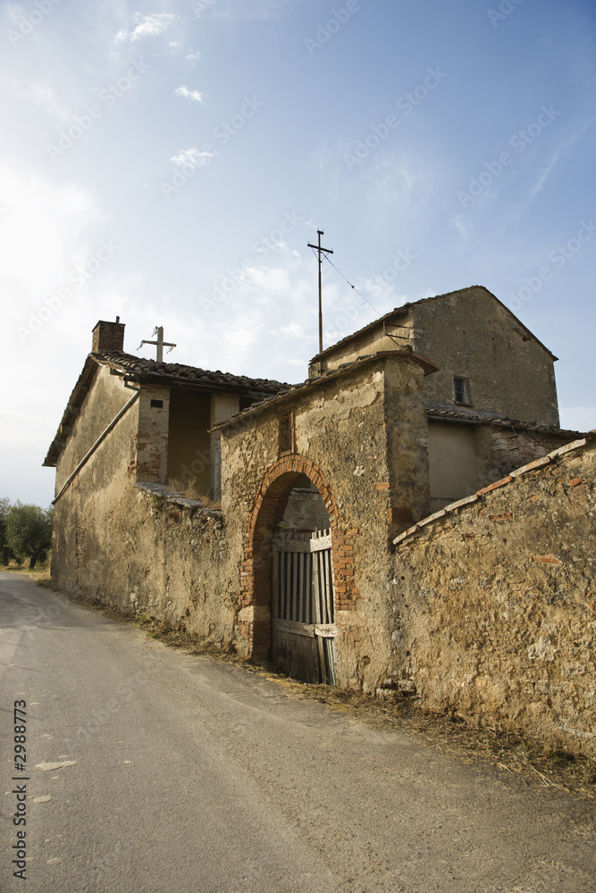 Stone building with gated archway in Tuscany.