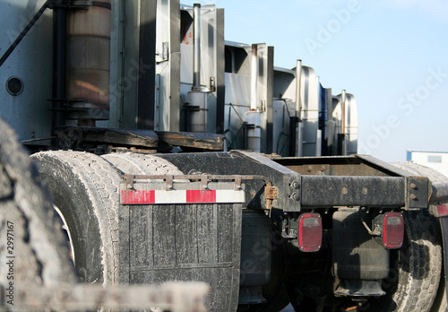 rear view of a fleet of parked semi tractors