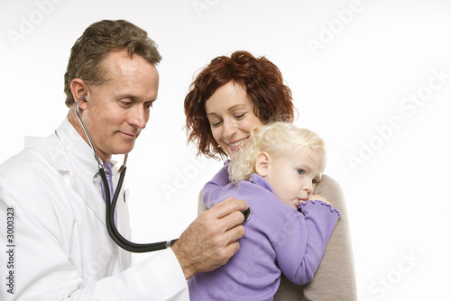 mother holding her daughter while doctor uses stethoscope.