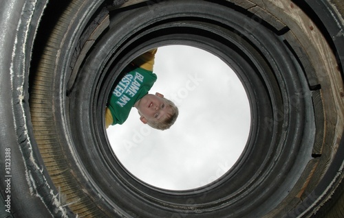 boy looking through tires