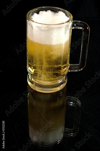 mug of beer reflecting on black surface
