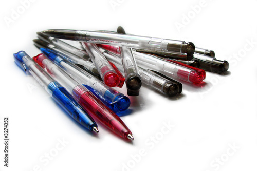 Plusieurs stylos à bille bleus noirs et rouges en plastique sur fond blanc 