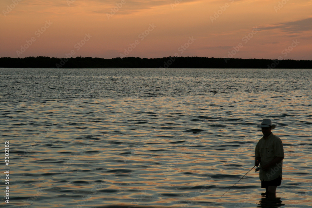 lone fisherman in water at sunset