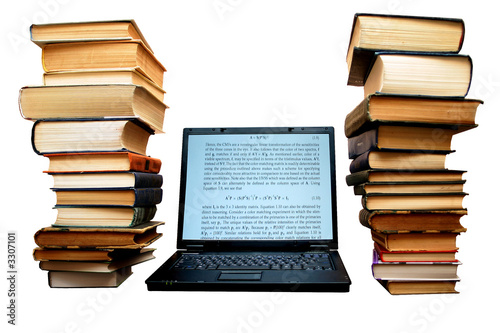 Two large piles of books next to  laptop photo