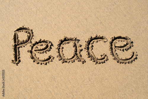 peace, written on a sandy beach.