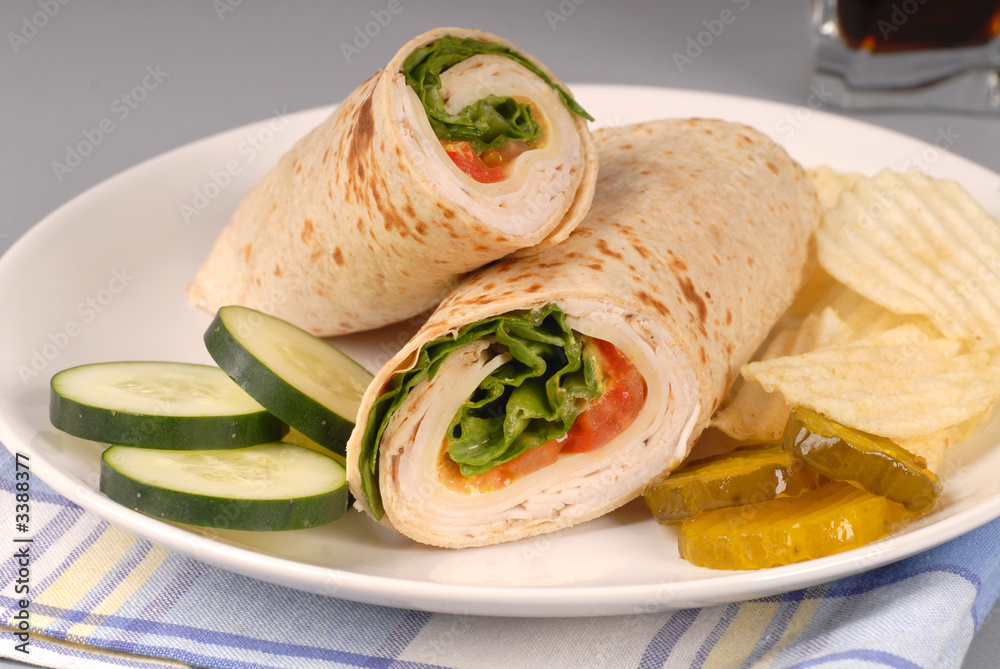 a turkey wrap with swiss cheese, pickles, cucumbers and chips a turkey wrap with swiss cheese, pickles, cucumbers and chips