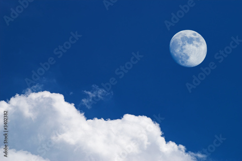 white clouds and full moon over deep blue sky