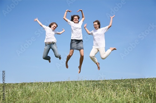 Three girlfriends in white T-shorts jump simultaneously