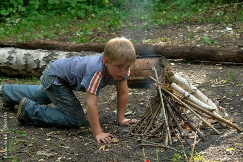boy kindles bonfire in the deciduous forest