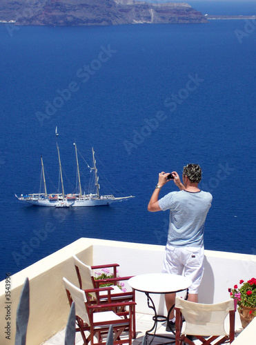tourist taking a holiday snap of a boat in santorini