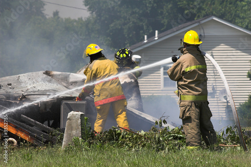 Fire fighters look for victums in debree of burned out home photo