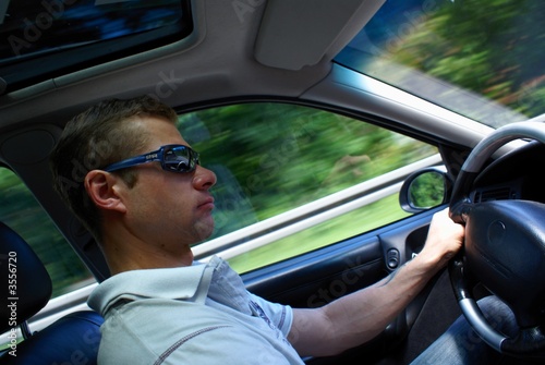 A young man driving a car in the drive. 
