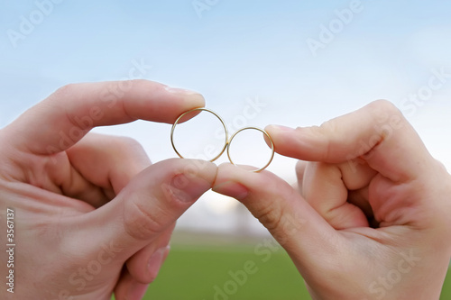 bride and groom holding two wedding rings close to each other