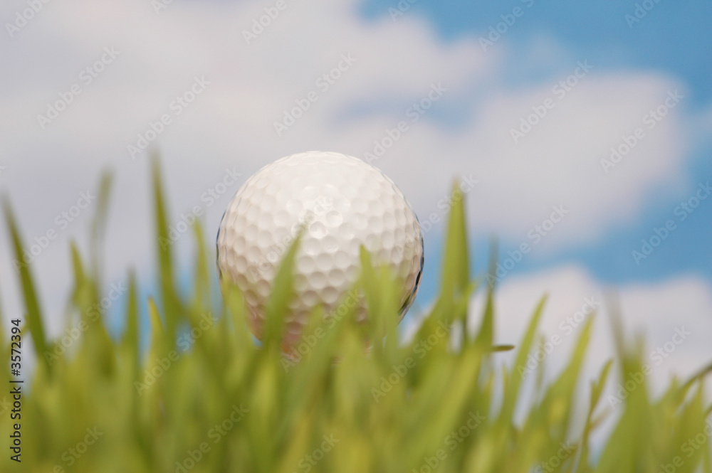 Golf ball and green grass against the blue sky Golf ball and green grass against the blue sky