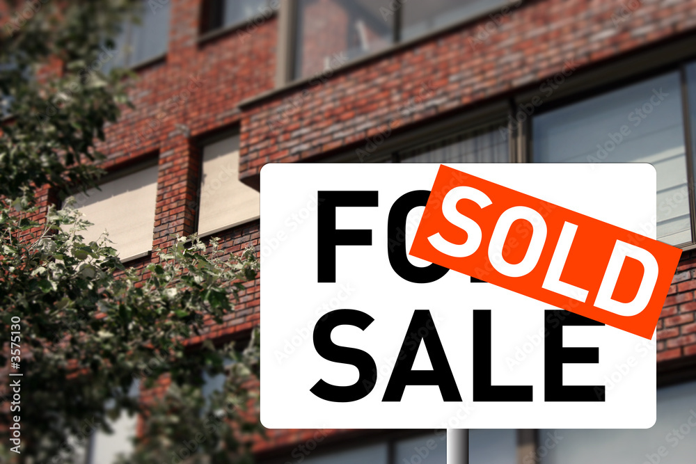 Fototapeta premium A sold sign and a house on the background