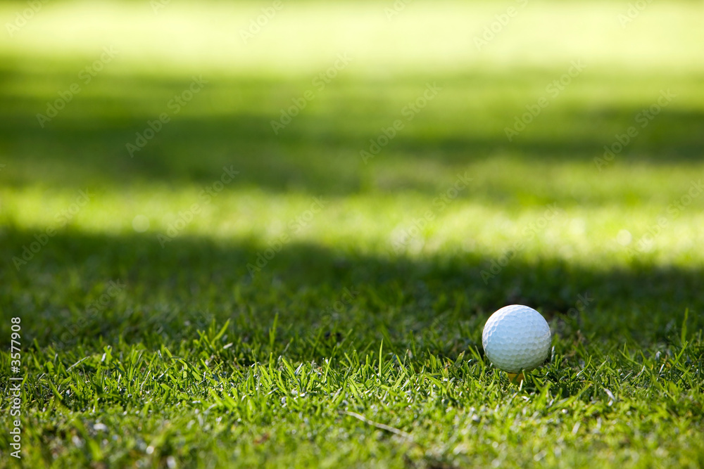 Golfball on yellow tee, soft shadows on background Golfball on yellow tee, soft shadows on background