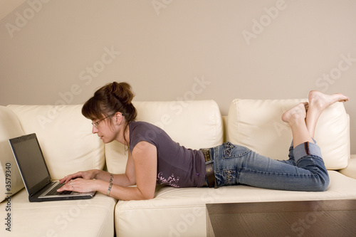 women lies on the sofa and working on laptop