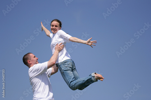 Beautiful young girl and young man have fun against blue sky