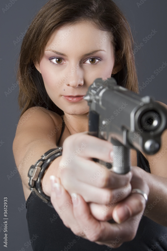 Attractive brunette pointing handgun towards camera Attractive brunette pointing handgun towards camera