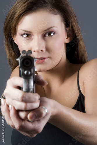 Attractive brunette pointing handgun towards camera