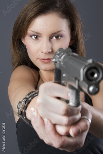 Attractive brunette pointing handgun towards camera