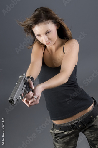 Attractive brunette pointing handgun towards camera